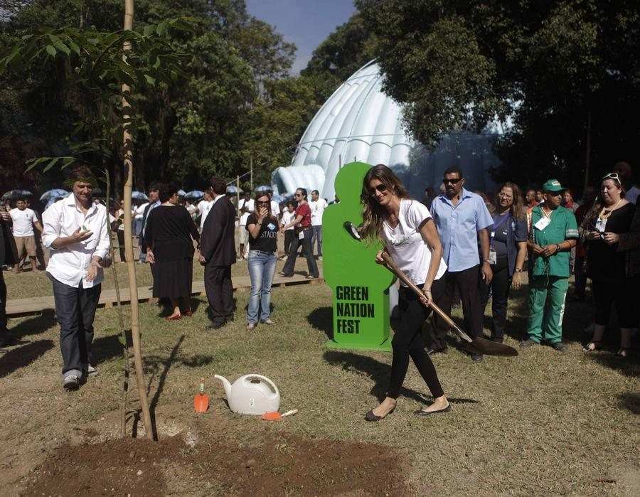 Gisele Bündchen kastuvu sodina medį „Green Nation Fest“ festivalyje Rio de Žaneire, aplink stovi lankytojai