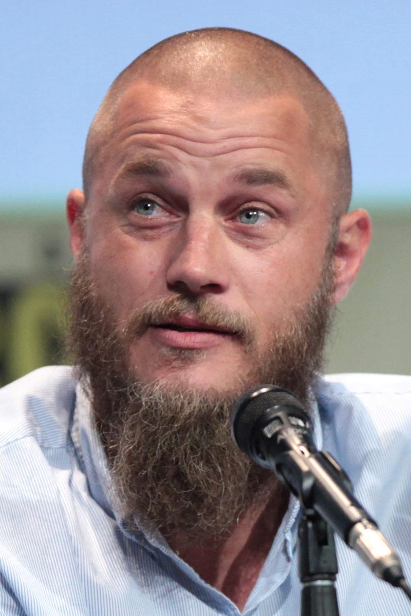 Travisas Fimmelis nuskusta galva ir ilga vešlia barzda kalba į mikrofoną San Diego Comic-Con 2015 m.
