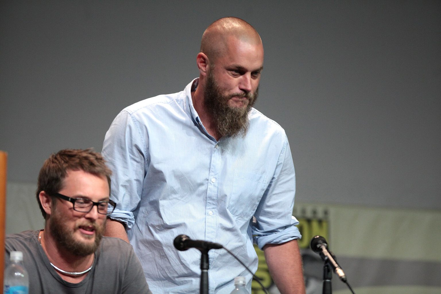 Travis Fimmel ir Duncanas Jonesas, 2015 m. Travisas Fimmelis stovi šalia sėdinčio režisieriaus Duncano Joneso prie „Comic-Con“ diskusijos stalo